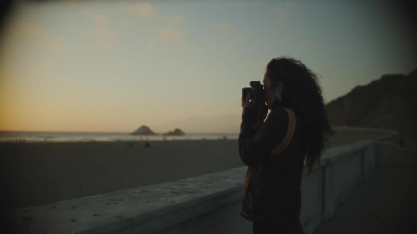 A woman on the beach taking some pictures during sun down
