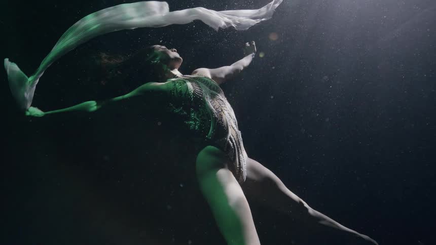 Artistic swimmer dances underwater in pool