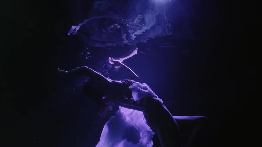 Woman floats underwater in a pool near the surface