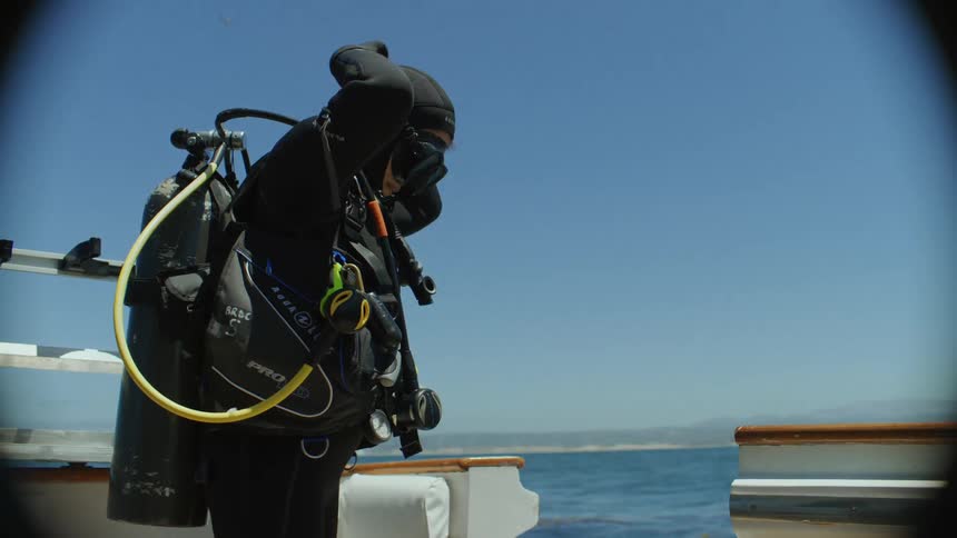 Woman in diving gear preparing on a boat in the open sea