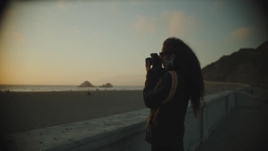 Woman taking her camera and capturing photos of the beach under a morning sky