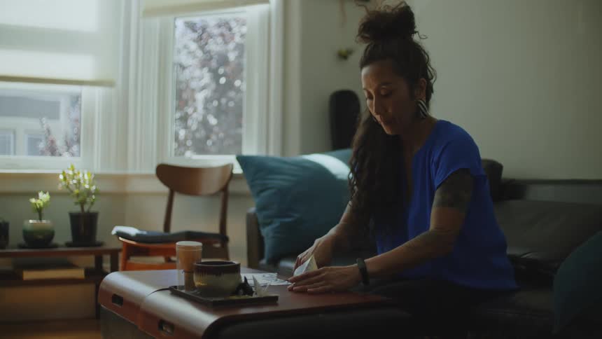 Woman sitting on the sofa making origami cranes
