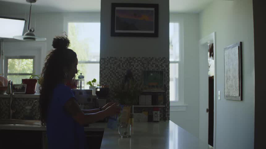 Woman standing in the kitchen at home preparing a coffee