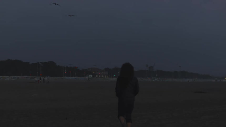 Woman walking on the beach at night