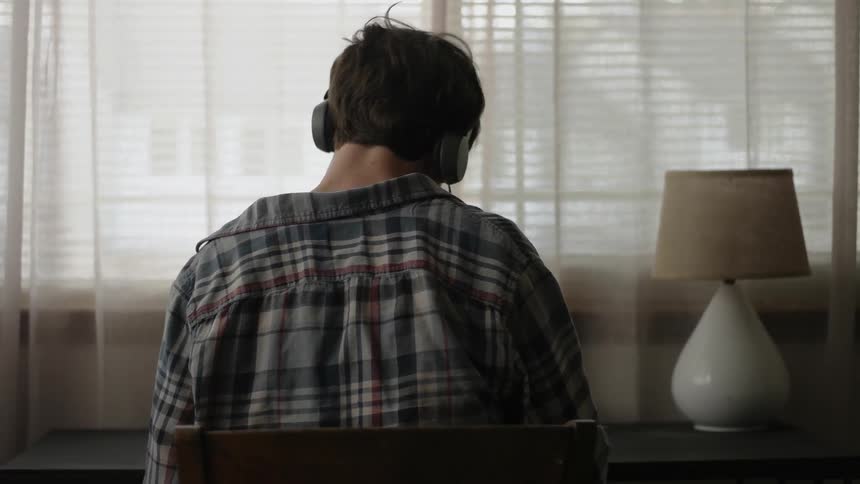 A man wearing headphones sits at a desk