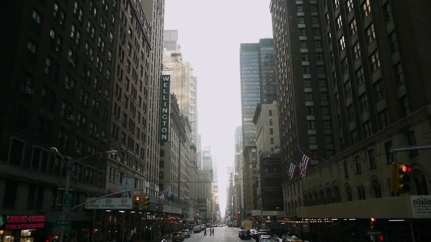 People cross the street in New York City with tall buildings