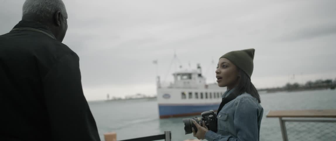 A woman holding a camera turns and talks to a man