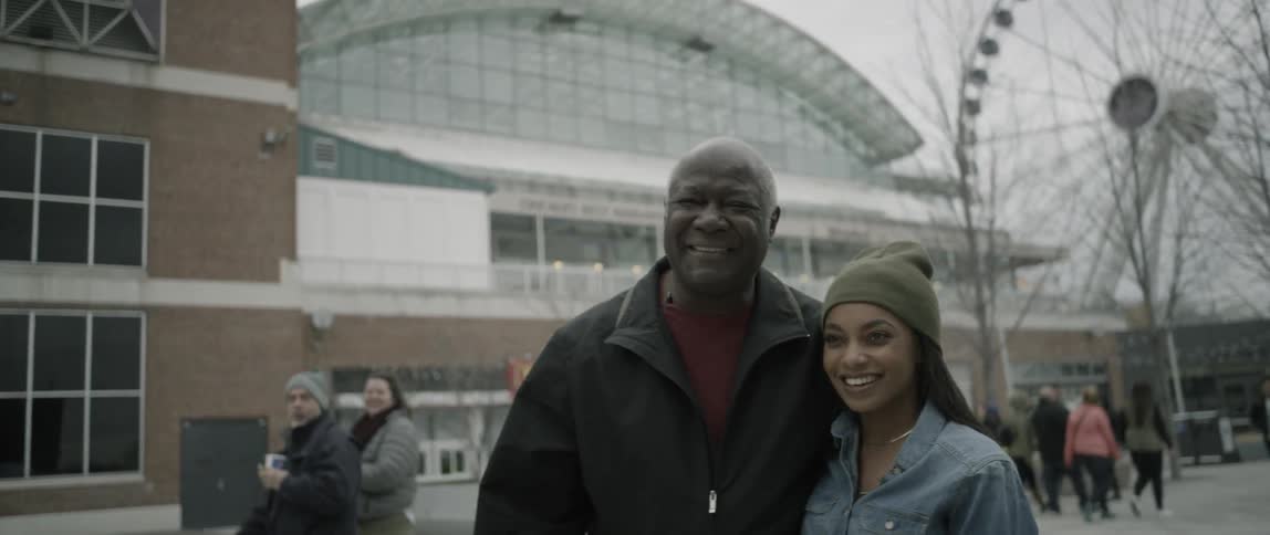 A man and woman stand in a busy square together smiling