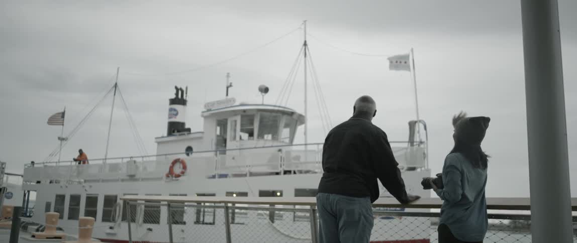 A man and woman wave to a docking ship