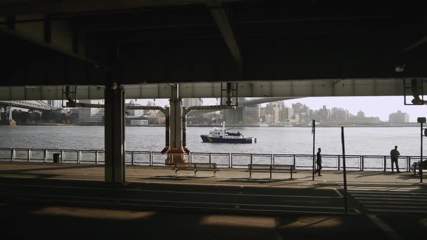 A boat can be seen in the water from under a bridge