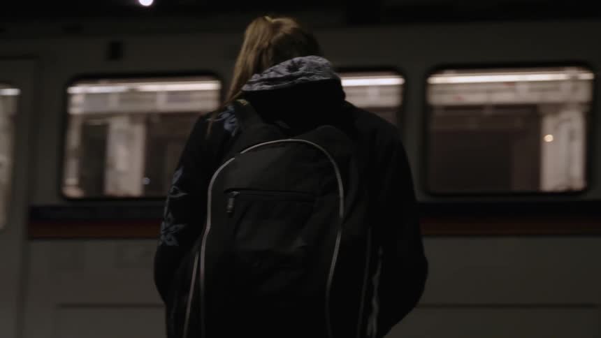 A woman stands outside at night as a bus rolls past