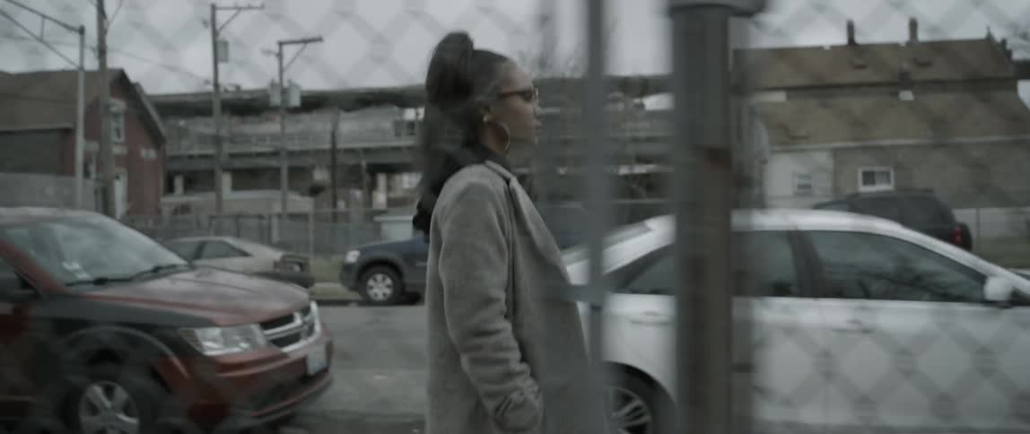 A woman walks past a fence on the sidewalk