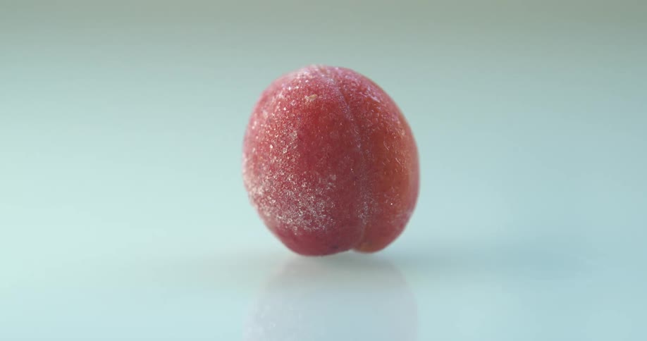 Ice crystals form on an apricot against a white surface