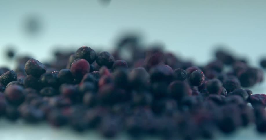 Fresh blueberries dropping slowly unto a smooth icy surface