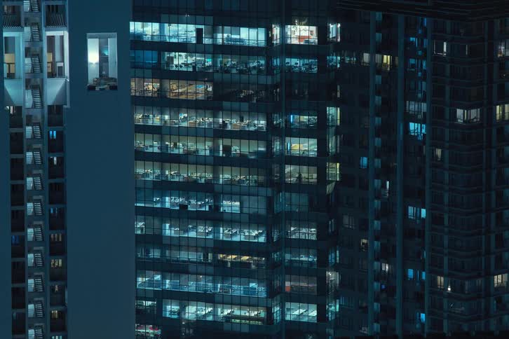 View of an allglass building at night in a metropolis in time lapse