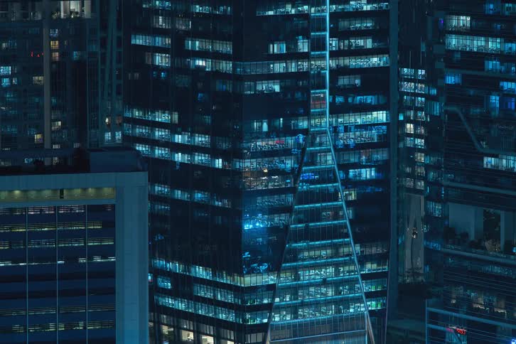 View of a building in the midst of a metropolis in a night time lapse with lights turning off and moving