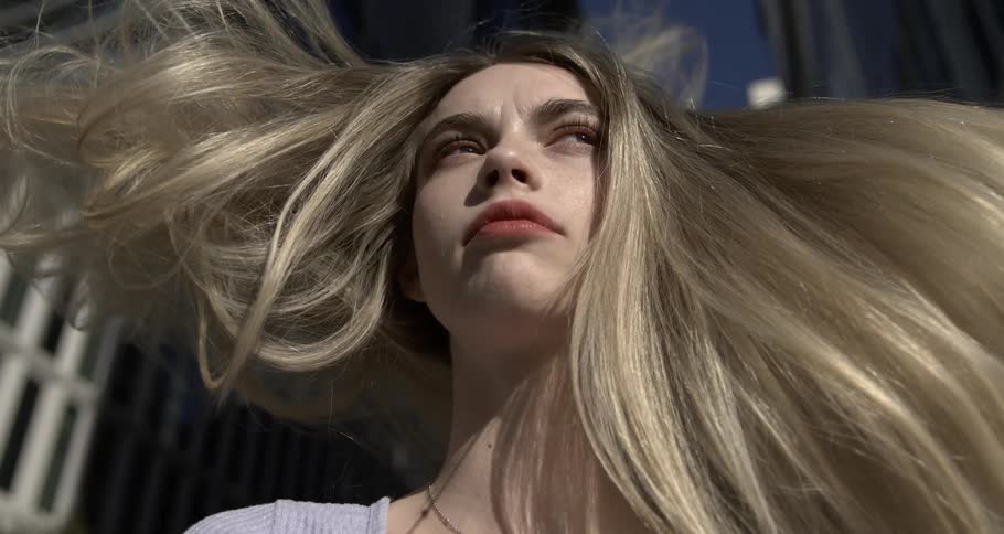 Portrait of a woman with her blonde hair flying in the air