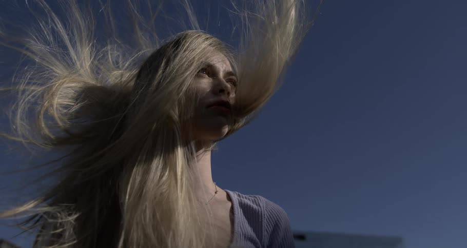 Portrait of a young blonde woman with her hair flowing in slow motion