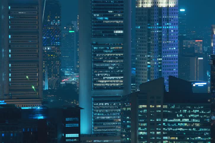 The exterior view captures tall buildings and office buildings in the city at night with lights flickering painting a vibrant and urban scene
