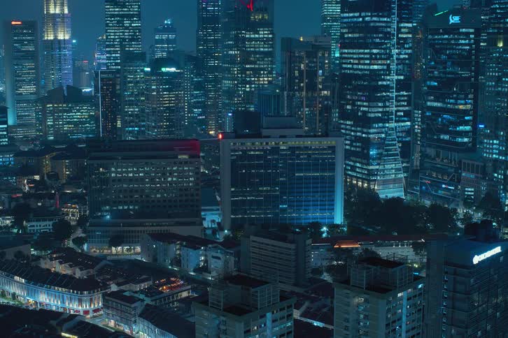 Lights turn on a off in windows reflecting a blue strobe effect across a metropolitan skyline at night