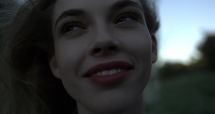 Portrait of a young woman smiling with her hair blowing backward in the wind in an outdoor natural setting
