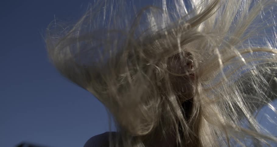 A womans hair blowing everywhere in a strong wind