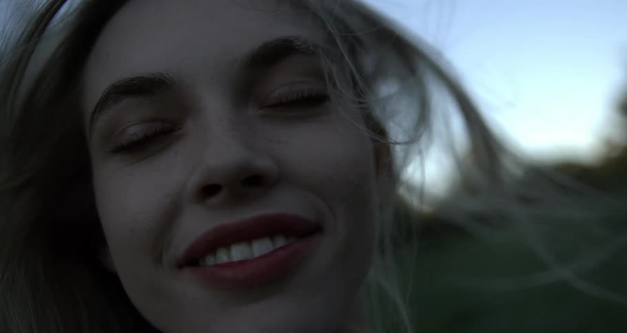 Portrait of a young woman smiling with her hair blowing backward in the wind in an outdoor