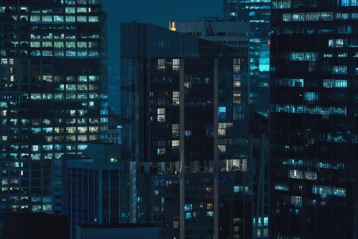 The exterior view captures tall buildings and office buildings in the city at night with lights flickering painting a vibrant and urban scene