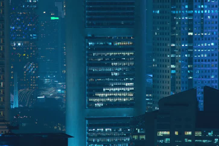 Blue reflected lights turning on and off strobing through skyscraper windows in the city at night
