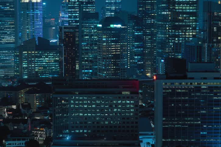 Exterior view of tall buildings and office buildings with flickering lights during night in the city