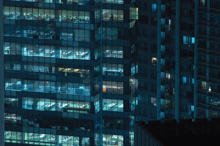 Modern mirrored building in a loop of lights turning on and off at night
