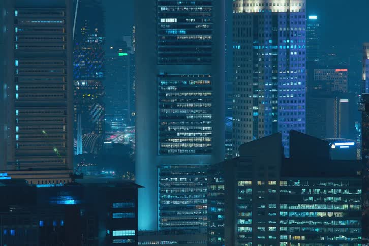 The exterior view captures tall buildings and office buildings in the city at night with lights flickering painting a vibrant and urban scene