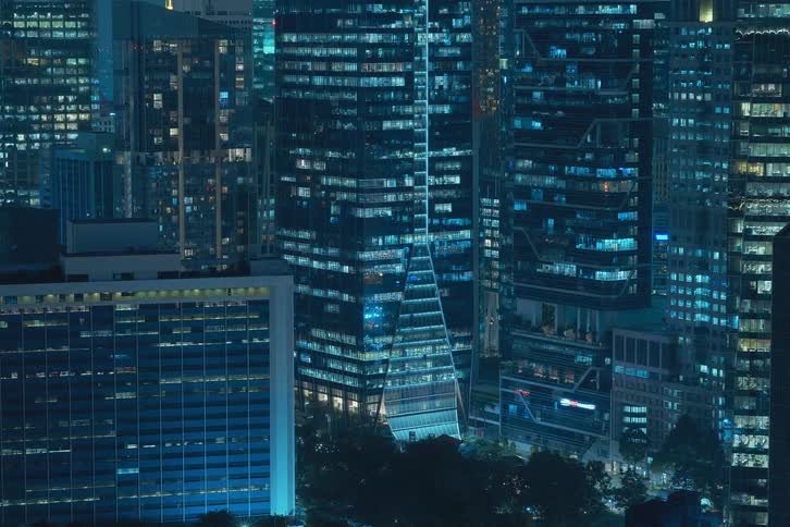 The exterior view captures office buildings and tall buildings in the city at night with lights flickering highlighting the bustling and dynamic nature of urban workspaces