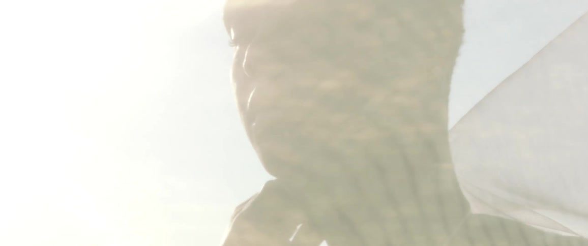 A womans face emerges from behind a white veil