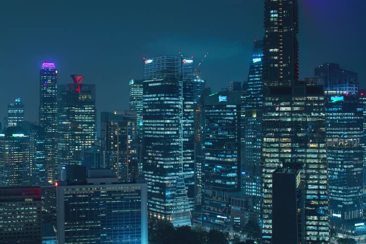 Glass skyscrapers in metropolitan city at night illuminated as the window lights turn on together