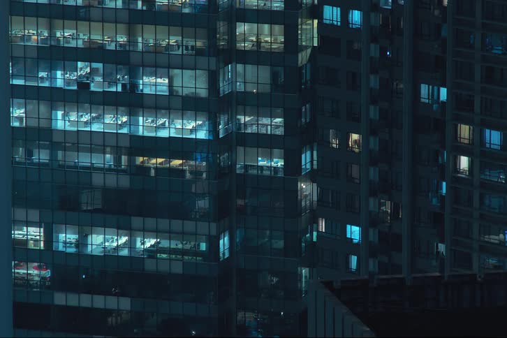 An office building with mirrored windows turning on together