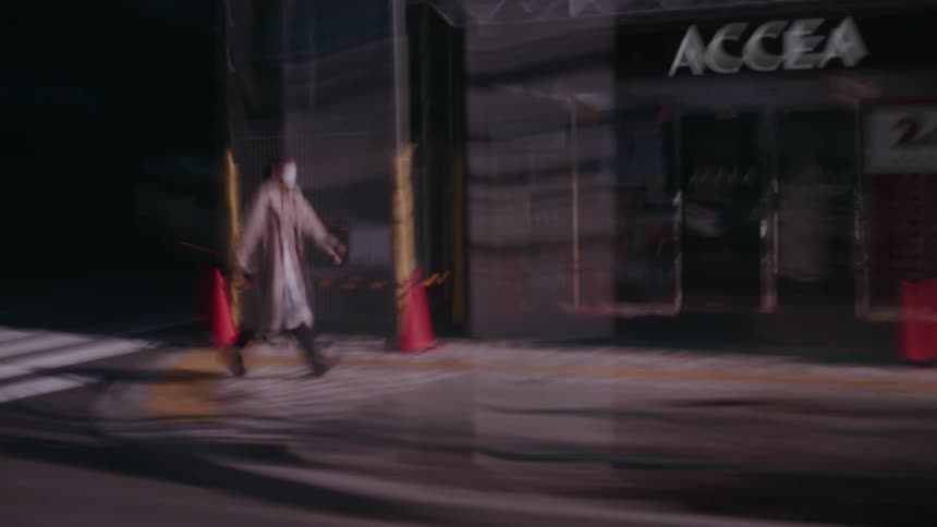 Blurry image of an adult walking down the sidewalk in an urban area