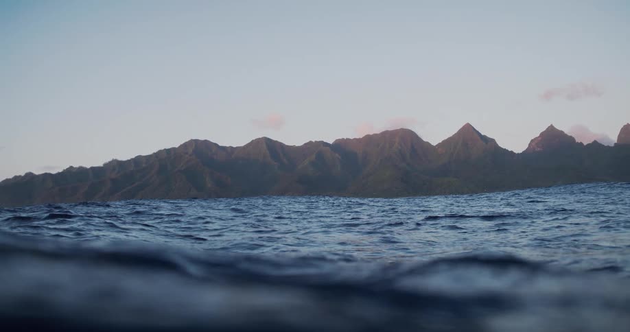 View of ocean waves with a mountain range on the horizon in the morning