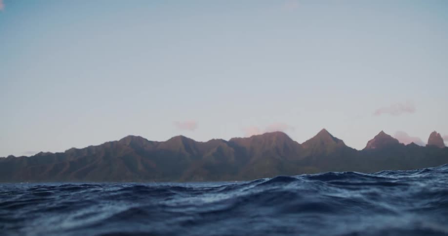 Sea with gentle waves with mountains on the horizon during the day