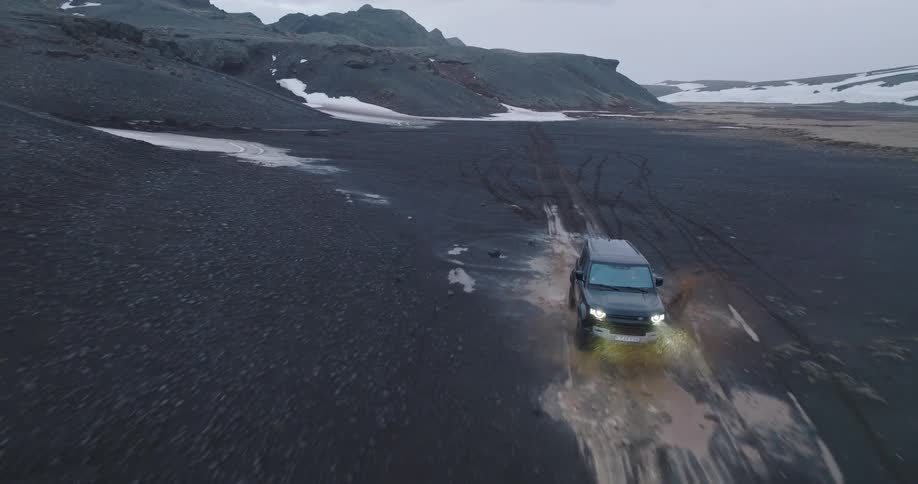 An off road car passing through a puddle of water in a black earth environment