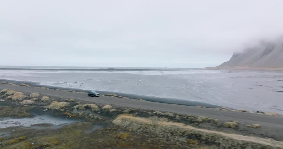 A car driving along a deserted road on the sea coast