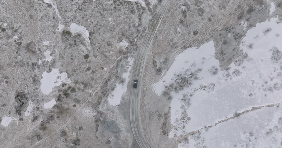 Aerial panorama of a vehicle moving on a street amidst an environment with grayish ground