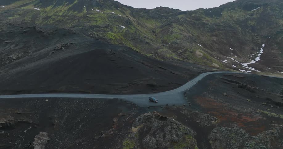 Aerial panorama of a vehicle parked on a cliff by the mountains