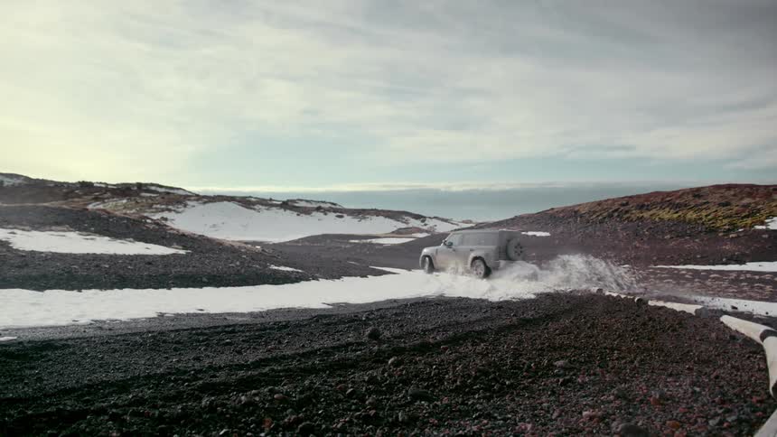 Vehicle speeds across ground skidding as it kicks up dirt and snow