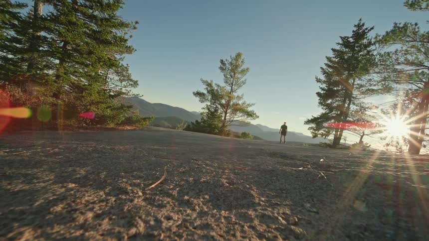 Male runner stops to appreciate the sun shining over the mountains before continuing his run