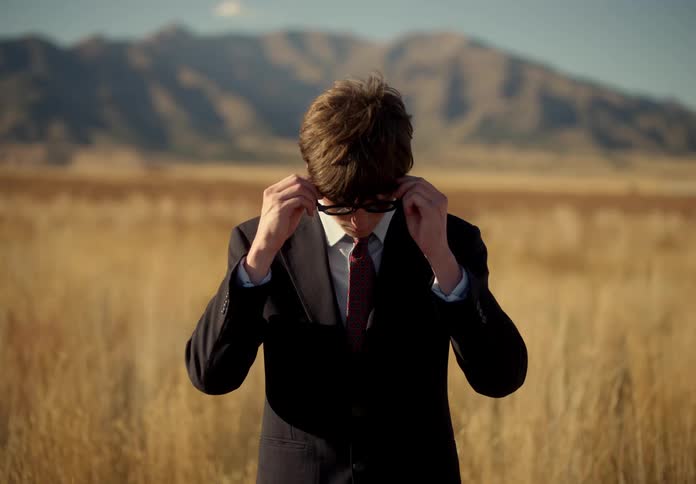 A man in a suit lost in a field on a hot day