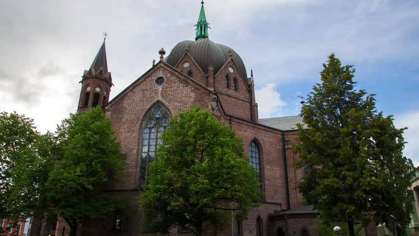 View of a church with trees around it in the midst of a city in timelapse
