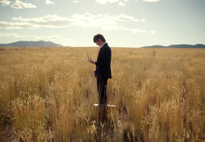 A man standing in a deserted field wearing a suit