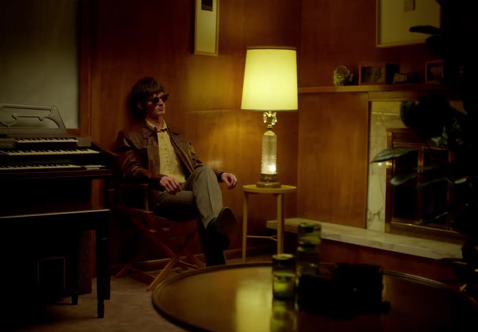 Man sitting in a chair in a room and putting on sunglasses