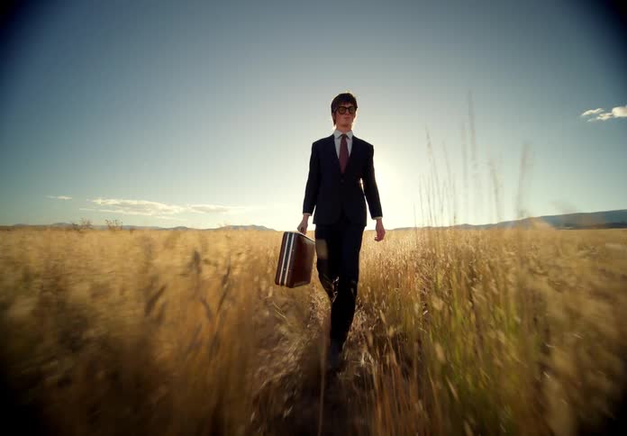 A man walking through a grassy field on a hot day